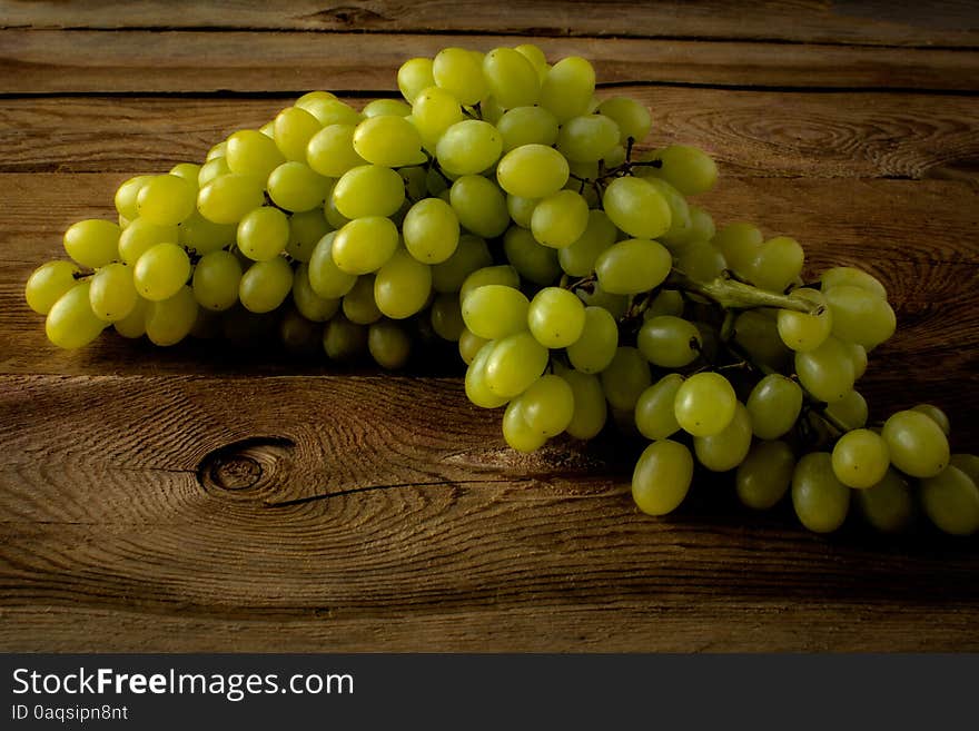 Bunch of green grapes on a dark wooden background. Selective focus. The toning. Bunch of green grapes on a dark wooden background. Selective focus. The toning