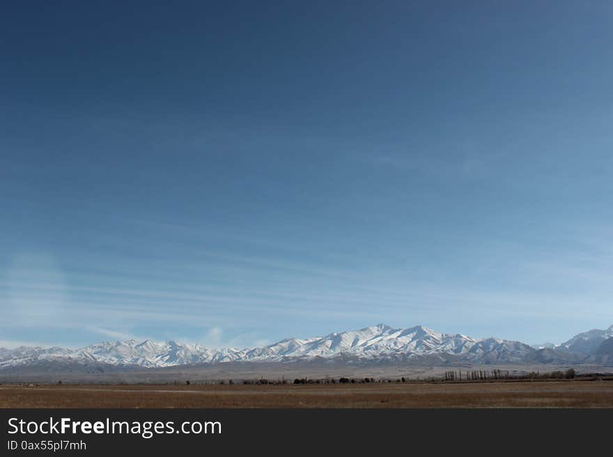 A small airport in the Talas region of Kyrgyzstan. Barely visible, it's just a one lane runway in the foreground. Mountains in the background. A mountainous, undeveloped and remote region of Kyrgyzstan. A small airport in the Talas region of Kyrgyzstan. Barely visible, it's just a one lane runway in the foreground. Mountains in the background. A mountainous, undeveloped and remote region of Kyrgyzstan.