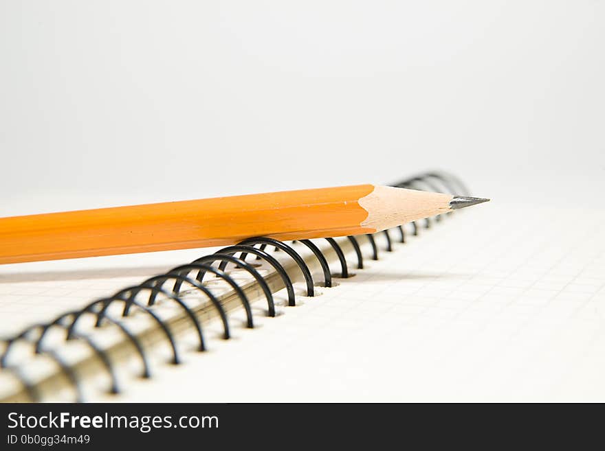 Opened notebook with a blank sheet and pencil on over white. Opened notebook with a blank sheet and pencil on over white