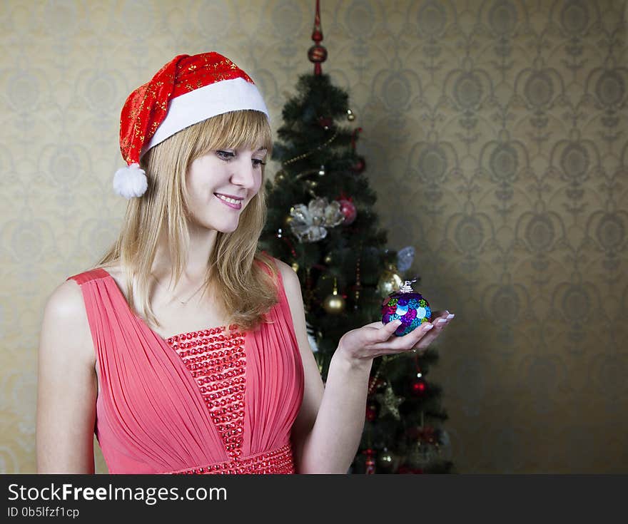 Young smiling girl in santa's hat and red dress holding a christmas toy. Young smiling girl in santa's hat and red dress holding a christmas toy