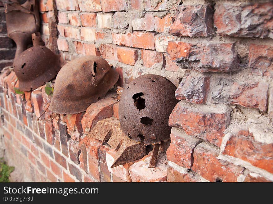 Three old rusty military helmets near the brick wall