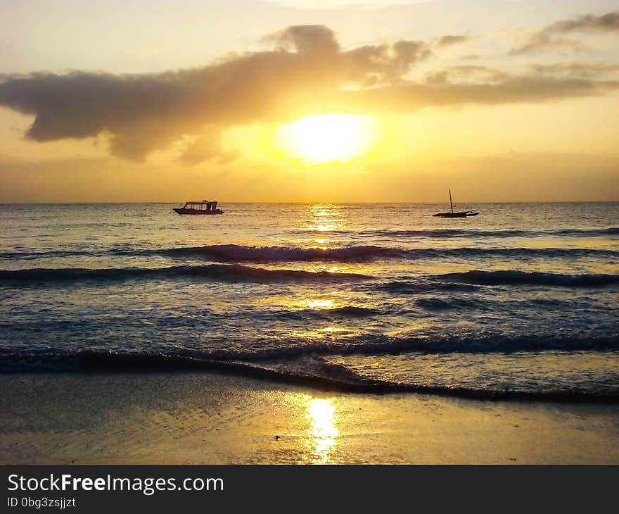 Morning sun, sunrise sky and clouds above sea waves on tropical sea sand beach, boats on skyline, Mombasa, Kenya. Morning sun, sunrise sky and clouds above sea waves on tropical sea sand beach, boats on skyline, Mombasa, Kenya