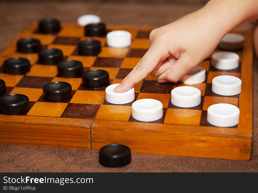 Child's hand moves the white piece to the chessboard. Child's hand moves the white piece to the chessboard