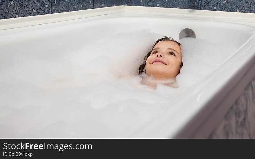 Little smiling girl lying in a bathtub closeup. Little smiling girl lying in a bathtub closeup