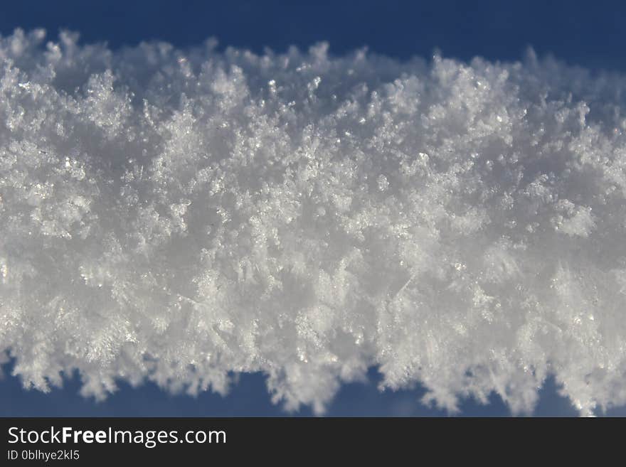 Snow and ice hanging on a thin wire outdoors in winter.  A rope of compact snow stretching horizontally across the picture. Snow and ice hanging on a thin wire outdoors in winter.  A rope of compact snow stretching horizontally across the picture.