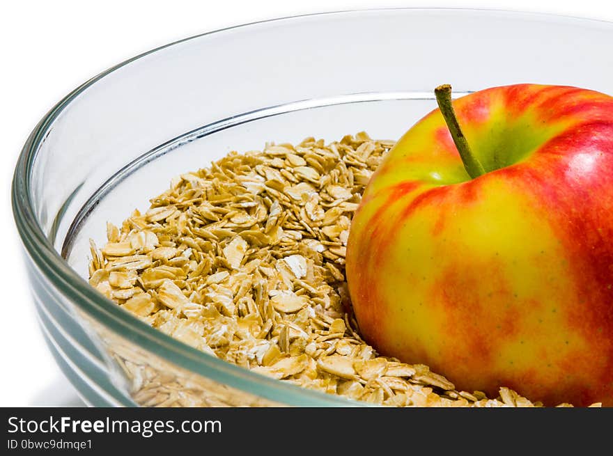 Apple on oat flakes background in a glass bowl &#x28;front view&#x29;. Red, Beige, White, Yellow, colors