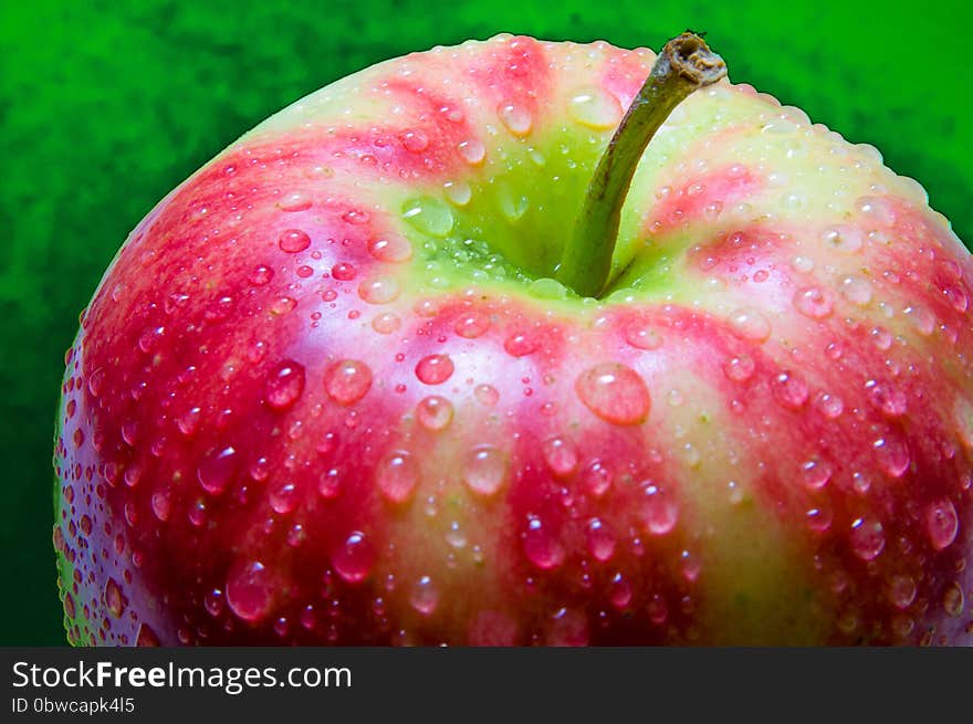 Drops of water on an apple closeup on a dark green textured background. Drops of water on an apple closeup on a dark green textured background