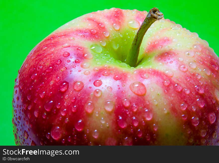 Drops of water on an apple closeup on a green background. Red, White, Yellow, Green colors