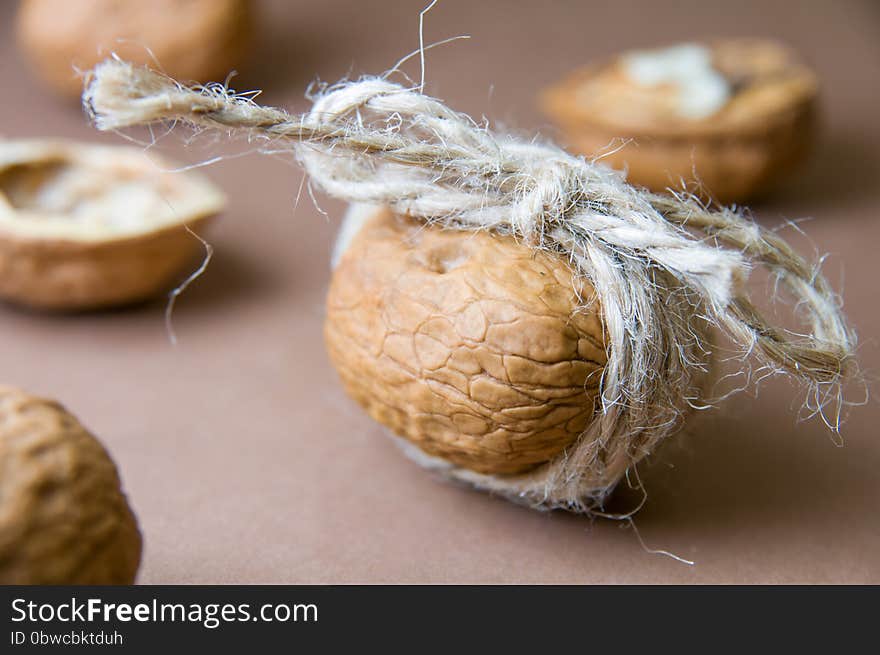 Walnut tied with twine on the background of blurred walnuts on a brown. Brown, Beige colors. Walnut tied with twine on the background of blurred walnuts on a brown. Brown, Beige colors