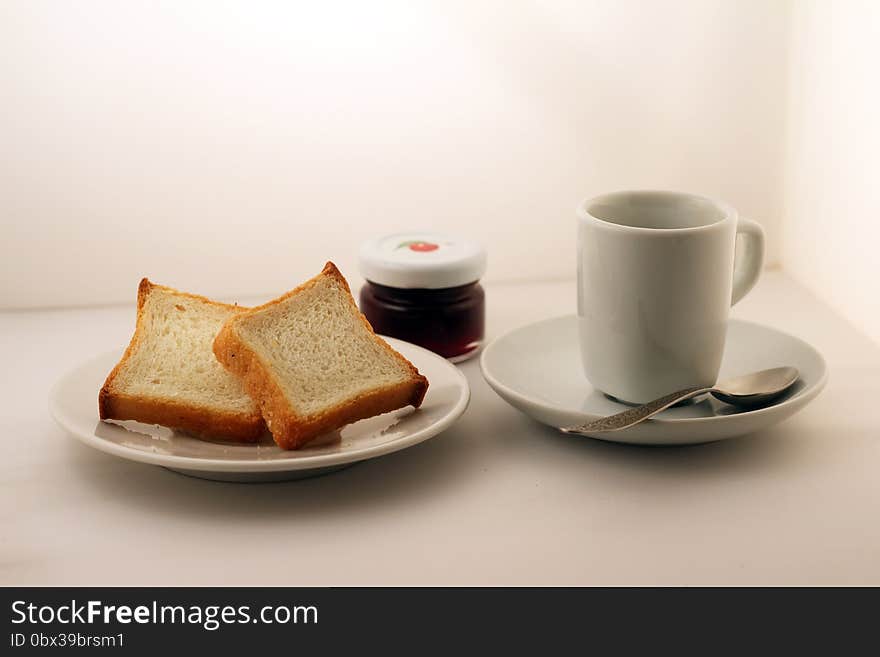 A mason jar of jam, cup of tea and bread on a white plate. A mason jar of jam, cup of tea and bread on a white plate