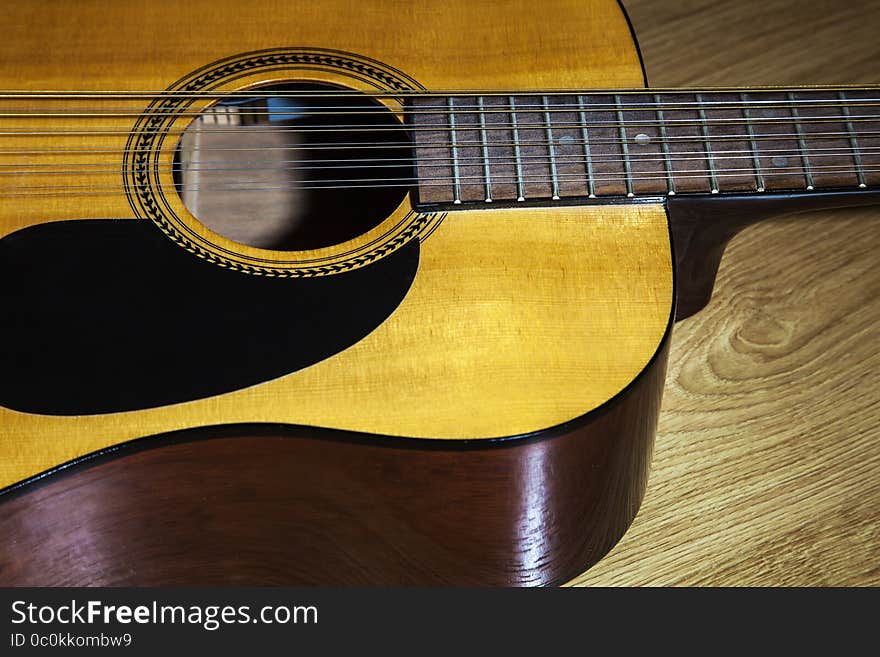 Body part of yellow 12 string guitar lying on the wooden floor closeup