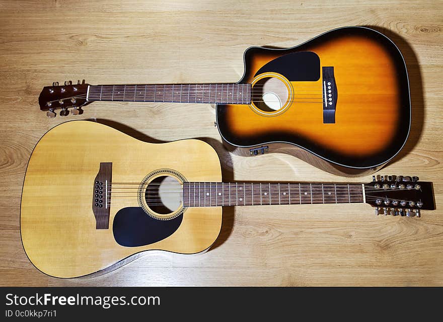 Two acoustic guitars lying on wooden floor closeup