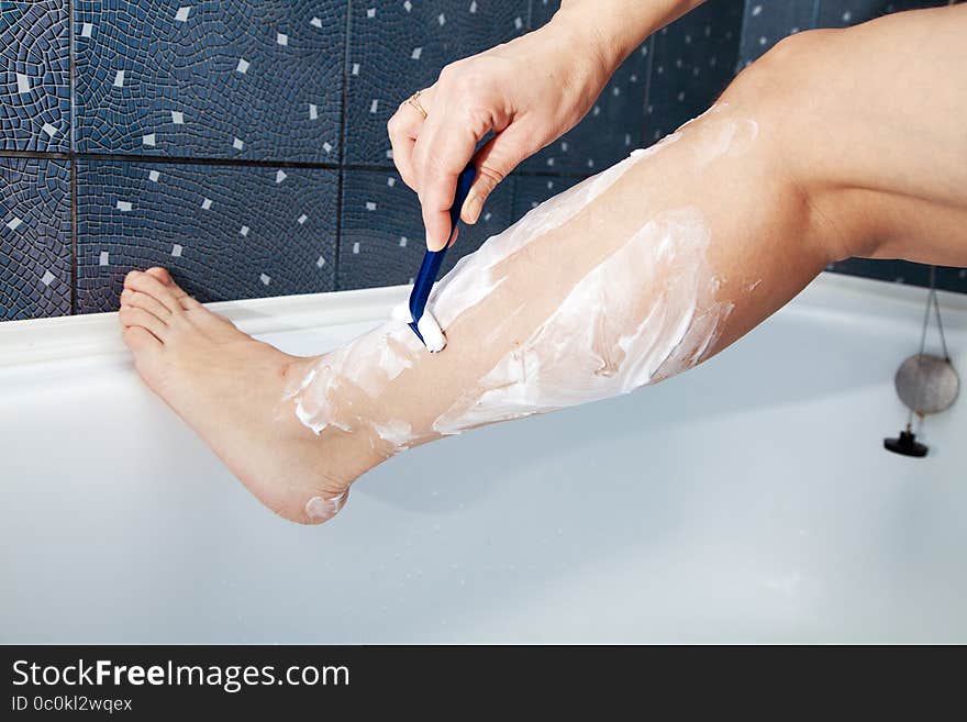 Woman shaving her leg in the bathroom. closeup