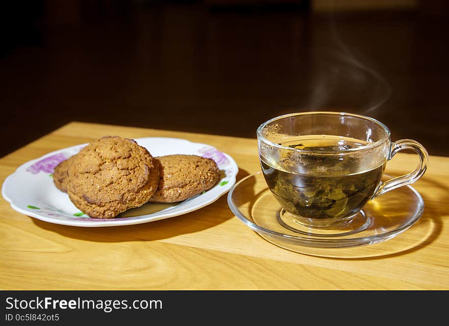 Glass cup with tea and biscuits on a plate closeup