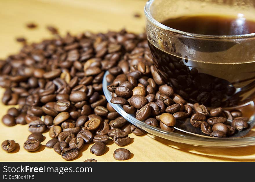 Coffee beans and a cup of coffee on the table closeup. Coffee beans and a cup of coffee on the table closeup