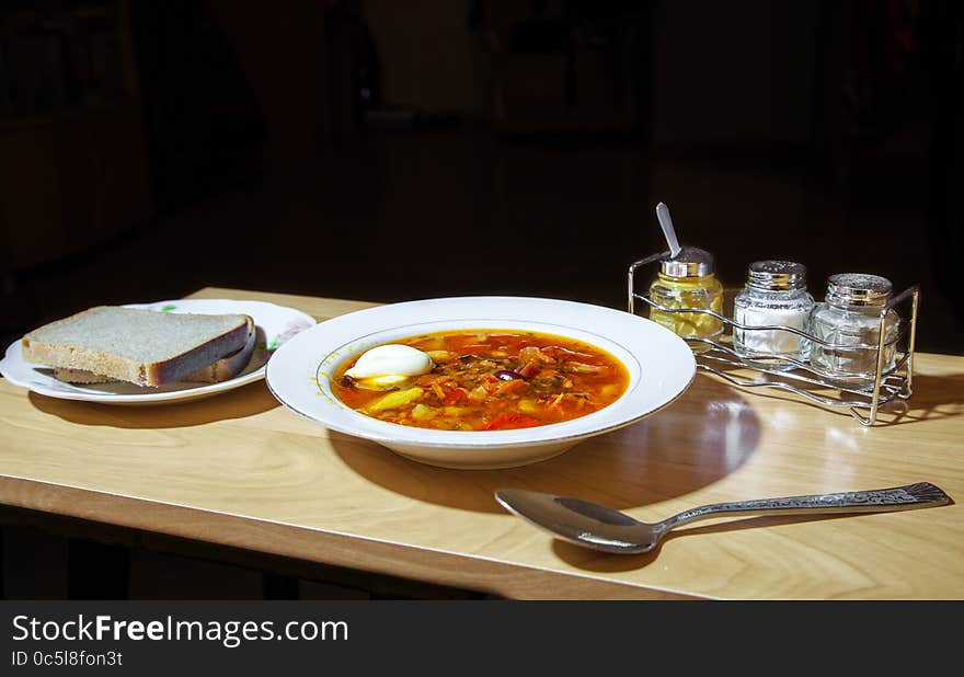 Plate of vegetable soup with two slices of bread on the table closeup