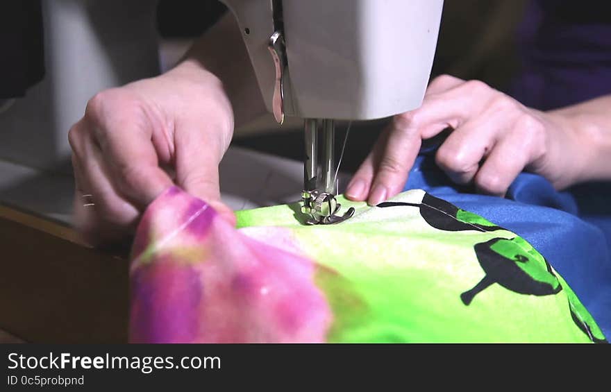 Woman's hands sewing on the sewing machine closeup. Woman's hands sewing on the sewing machine closeup