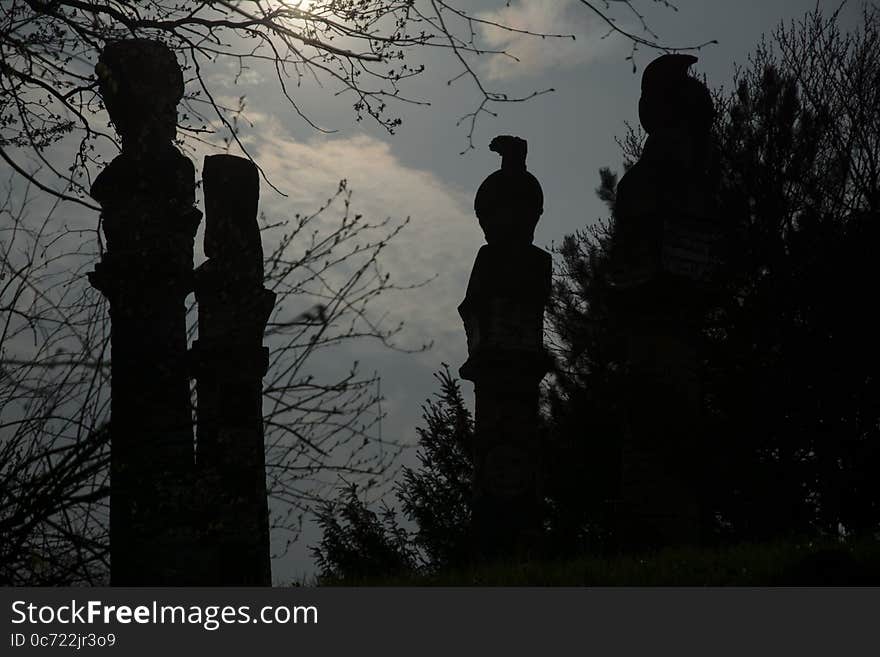 It is sunset. Four mysterious figures standing in the park. They аre mounted on the pillars. It is sunset. Four mysterious figures standing in the park. They аre mounted on the pillars.