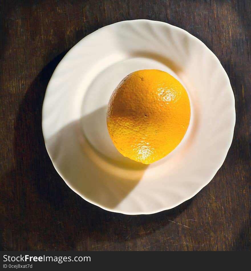 Ripe orange in white plate on wooden background