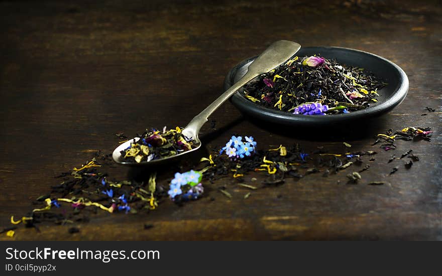 Dry tea in spoon and plate on wooden background . Dry tea in spoon and plate on wooden background .