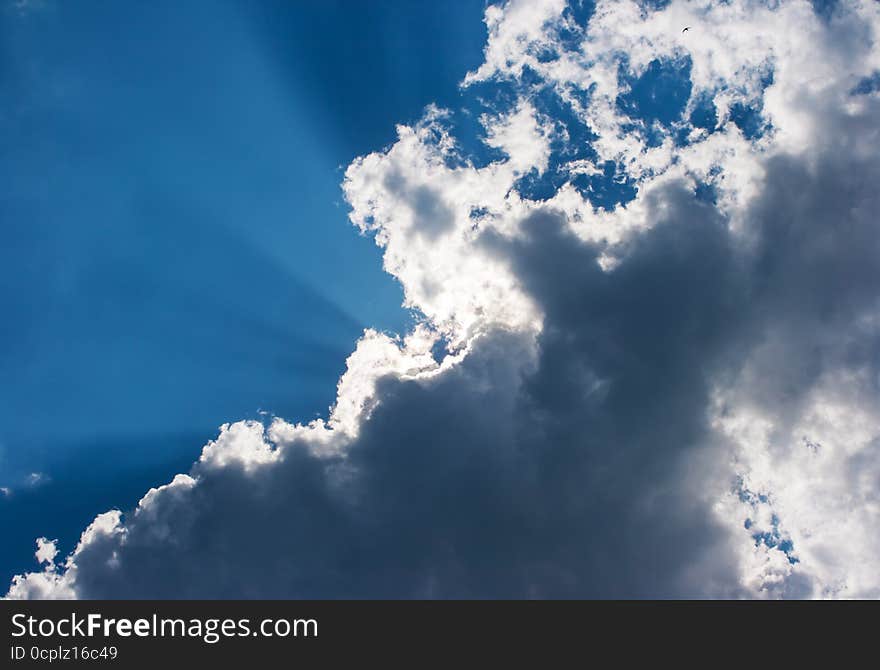 Sun's rays behind the cloud on blue sky. Sun's rays behind the cloud on blue sky