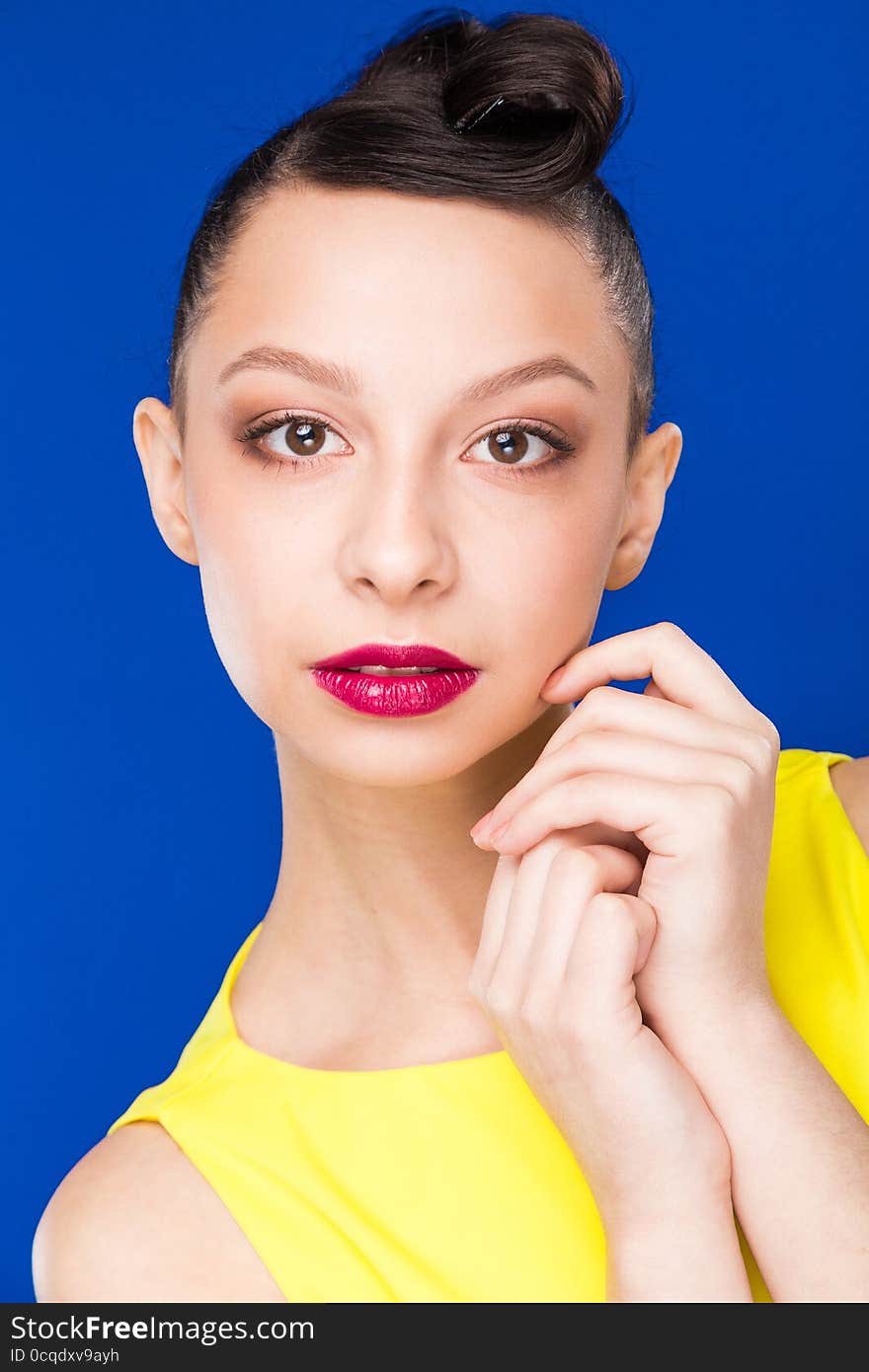 Portrait of a girl with hands on her face in a yellow dress. Portrait of a girl with hands on her face in a yellow dress