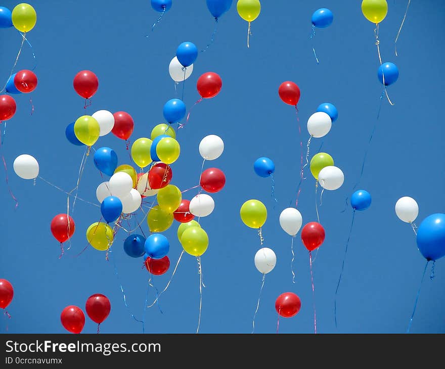 Bright balloons on streamers are floating off into a bright blue sky. Bright balloons on streamers are floating off into a bright blue sky.