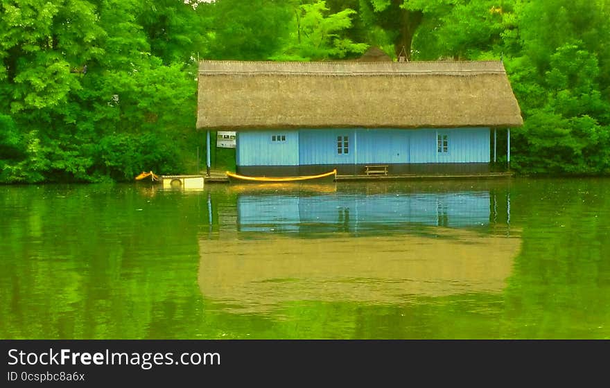 spooky interpretation with overfiltered view with blue wooden house on the green lake in autumn season. spooky interpretation with overfiltered view with blue wooden house on the green lake in autumn season