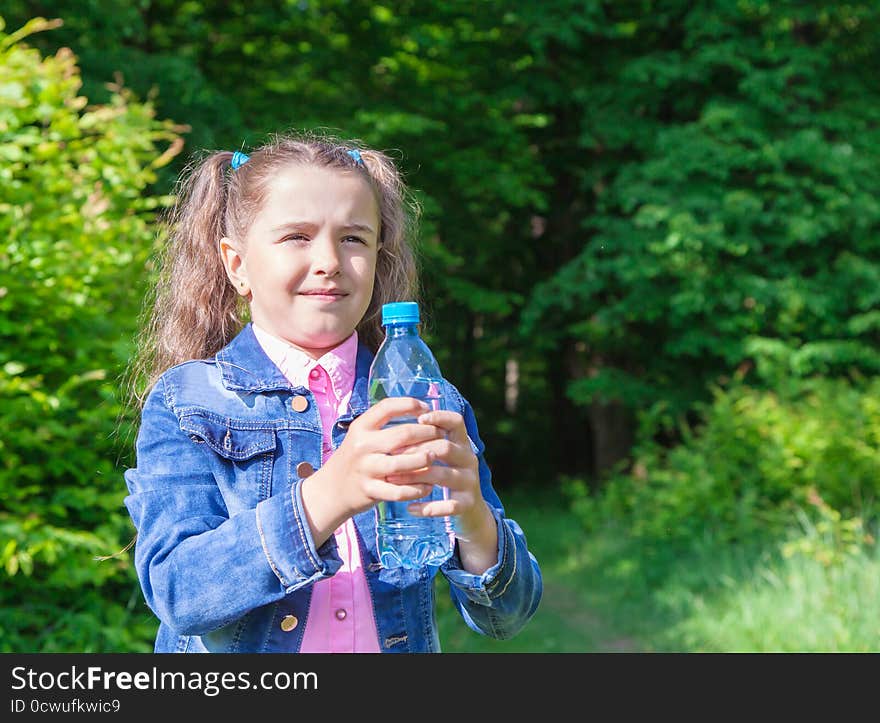 Girl in a denim jacket holding a water bottle outdoor closeup. Girl in a denim jacket holding a water bottle outdoor closeup