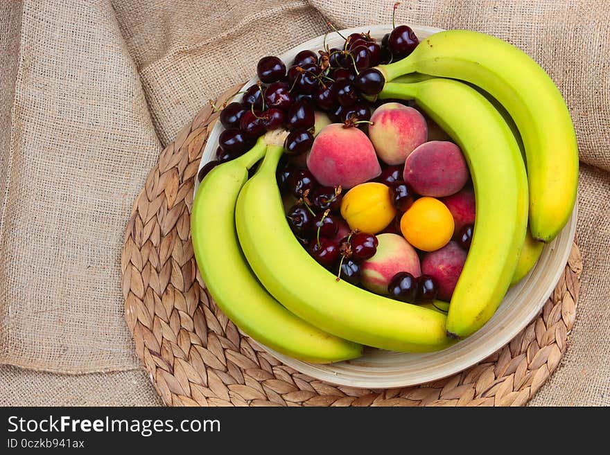 A Wooden Bowl of Fruits on a Wooden Background, Banana, Cherries, Peaches