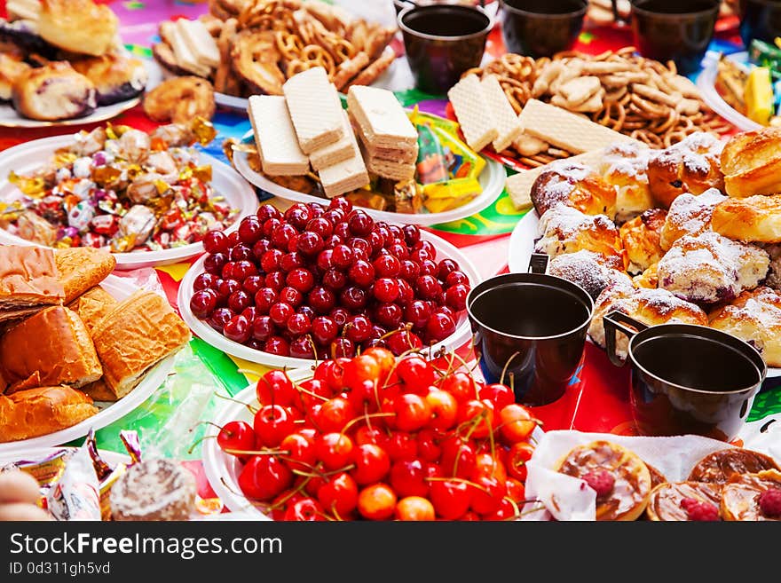 Festive table with sweets, chocolates, waffles, cherries outside on summer day. Festive table with sweets, chocolates, waffles, cherries outside on summer day