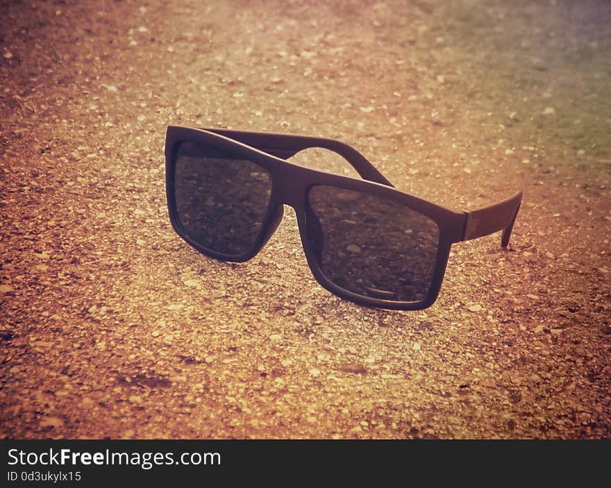 Black sunglasses on the beach in the morning