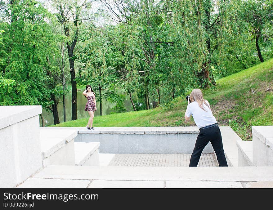 Photographer takes a woman standing on the stairs in the park