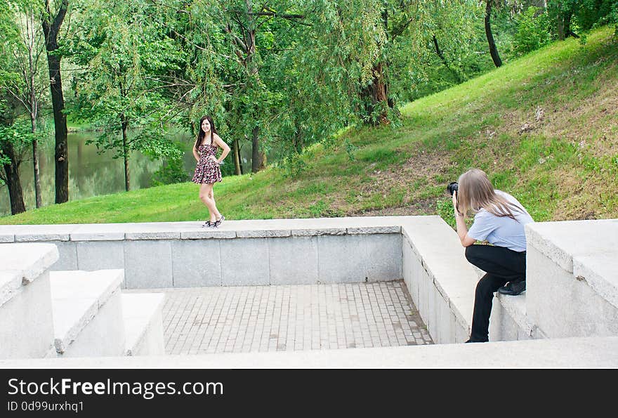 Photographer takes a woman standing on the stairs in the park