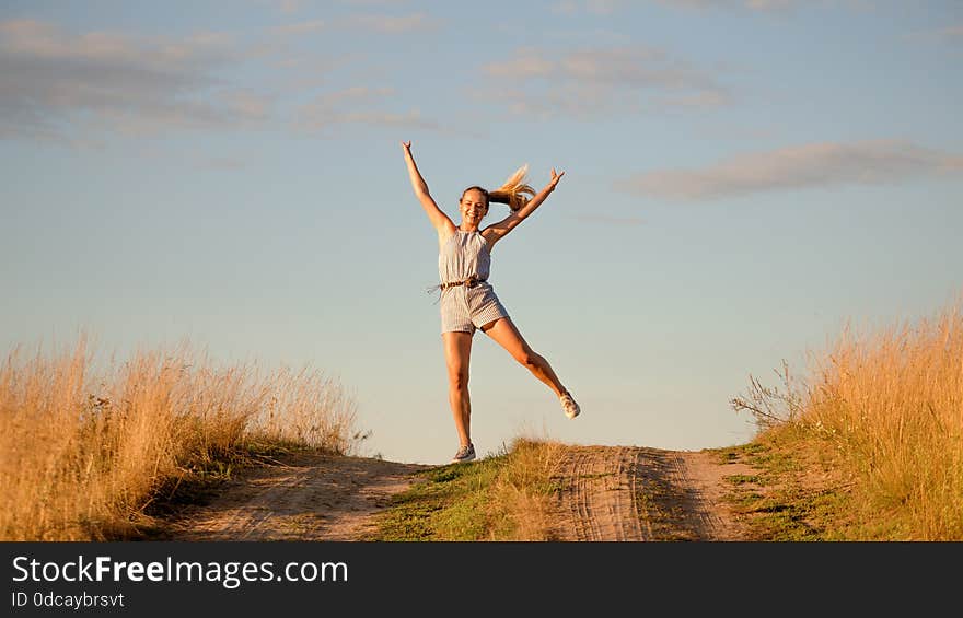 Happy beautiful young girl dancing in a field