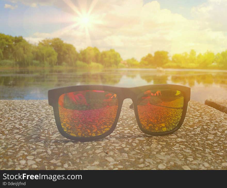 Picture with fashionable colorful sunglases in a sunny day of summer and beautiful landscape on the lake