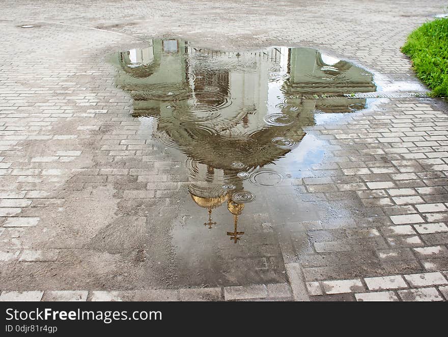 White church reflected in a puddle in the rain closeup