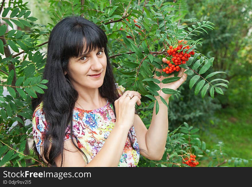 Beautiful young smiling brunette near rowan tree. Beautiful young smiling brunette near rowan tree