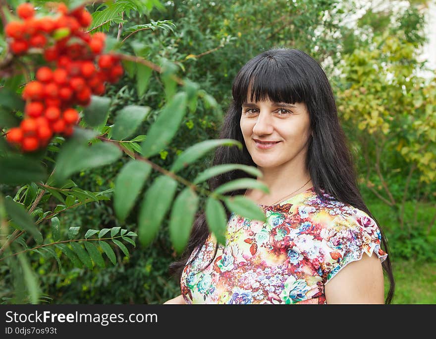 Portrait of a beautiful young brunette near rowan tree