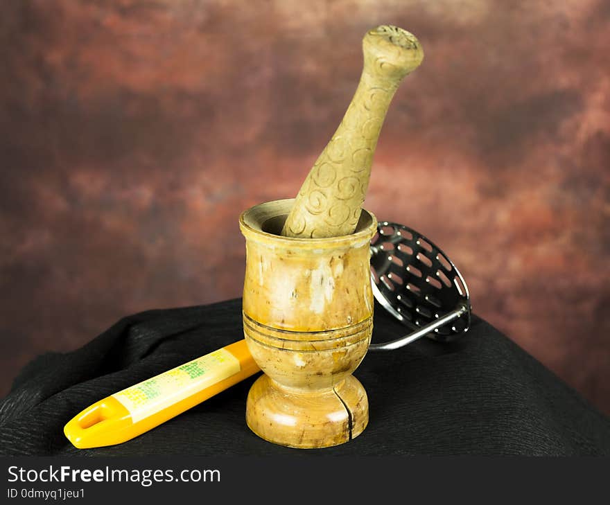 Mortar and pestle with potato masher on a black ground. Mortar and pestle with potato masher on a black ground.