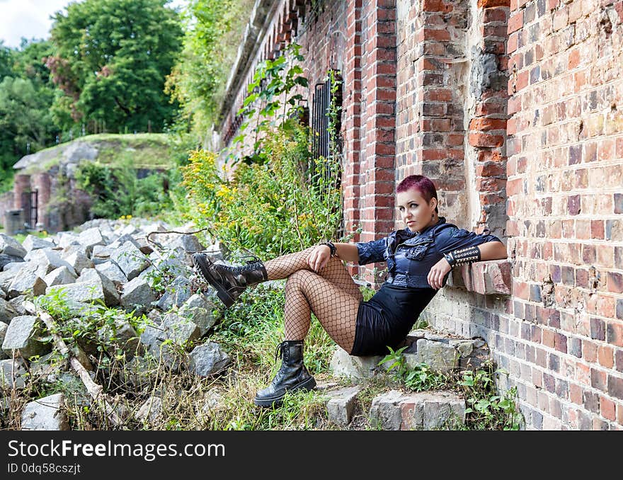 Punk girl sitting on the stone porch of an old abandoned castle. Punk girl sitting on the stone porch of an old abandoned castle