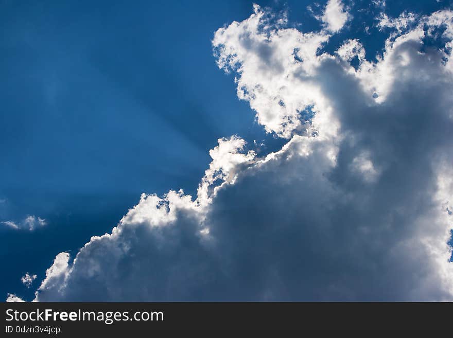 Sun's rays behind the cloud on bright blue sky. Sun's rays behind the cloud on bright blue sky