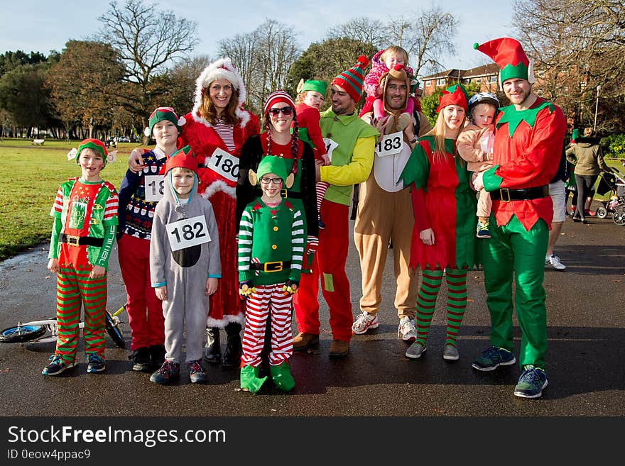 Group of adults and children dressed as elves standing on walkway on sunny day. Group of adults and children dressed as elves standing on walkway on sunny day.