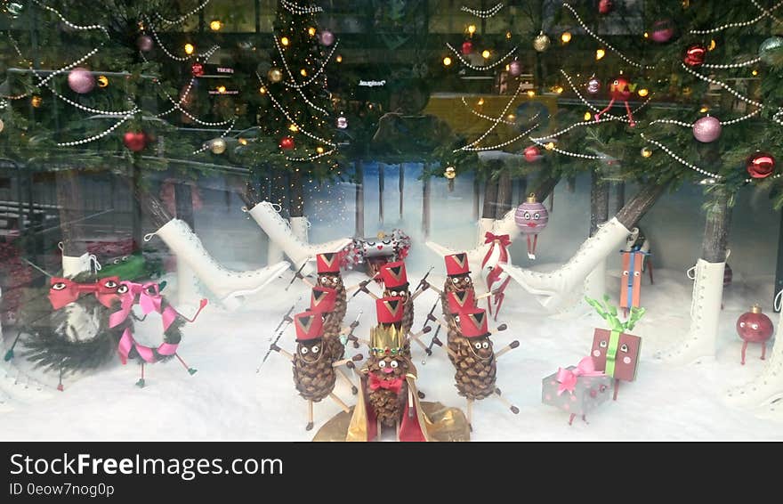 Christmas display with decorated pine cones, boots and ornaments on tree.