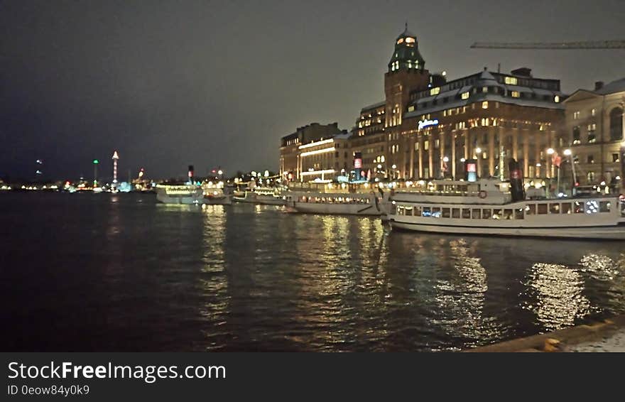 Night scene of architecture illuminated and reflecting in water along waterfront promenade. Night scene of architecture illuminated and reflecting in water along waterfront promenade.