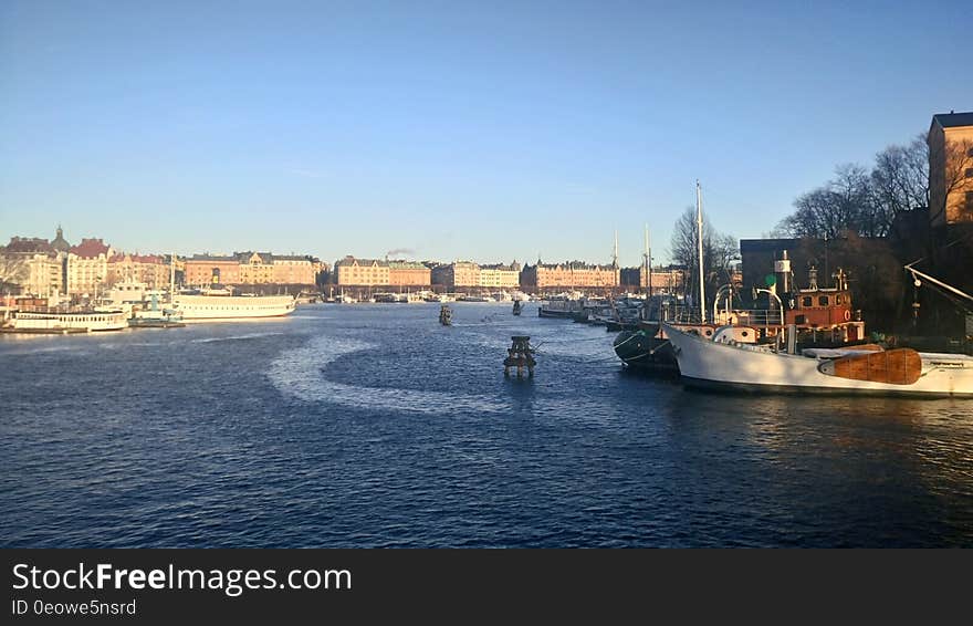 Panoramic view of a wide river flowing through a city with boats in the foreground.