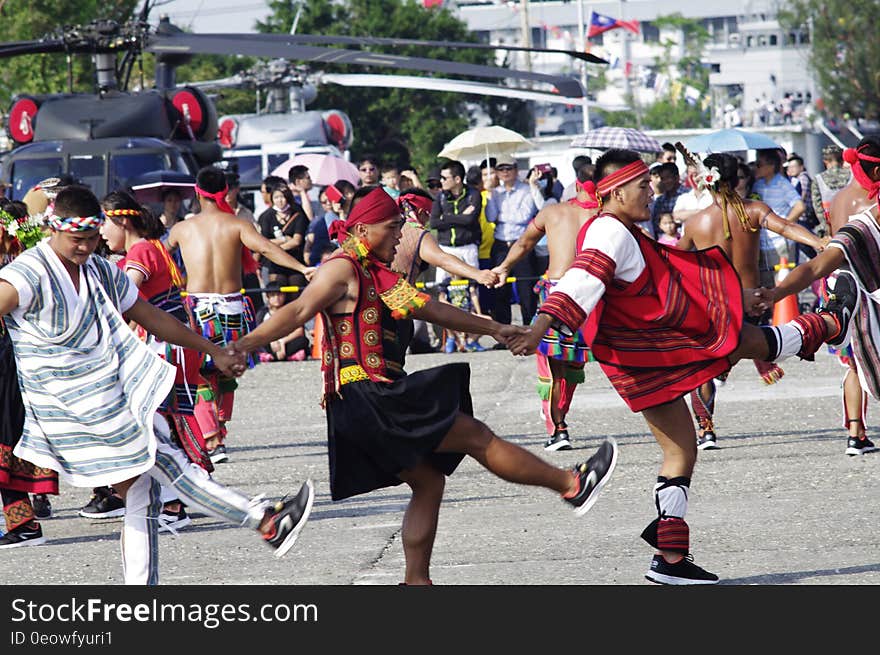 A parade of people dancing native dances in costumes.