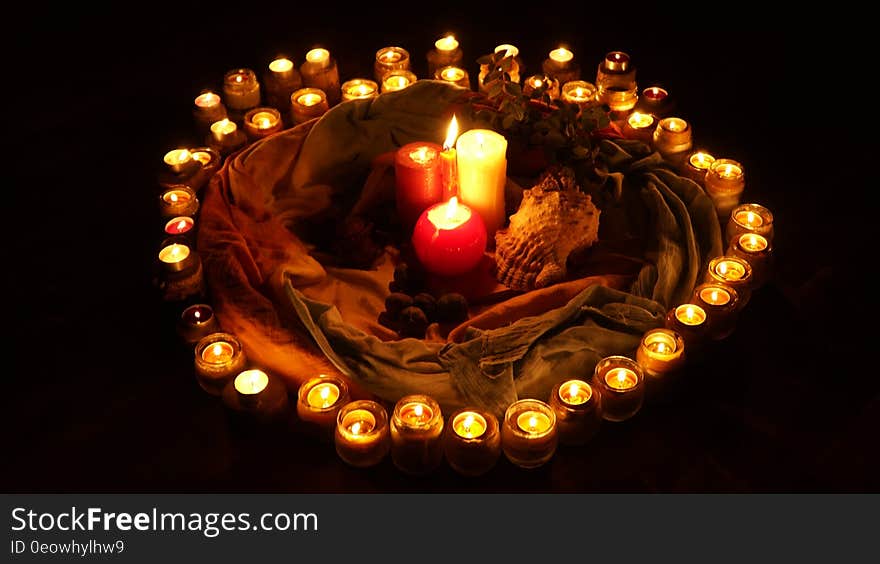 Circle of lit candles around candlesticks and shell with black background. Circle of lit candles around candlesticks and shell with black background.