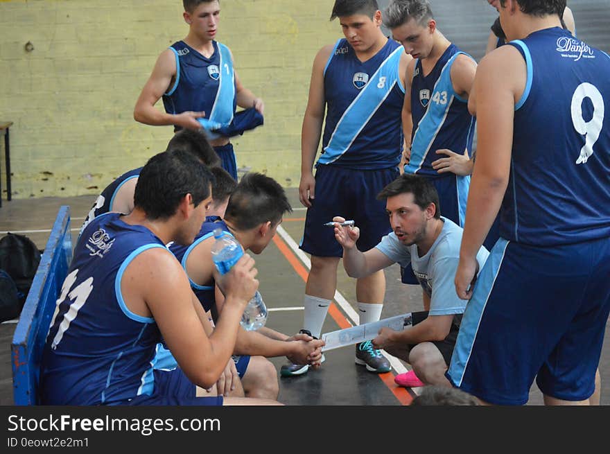 Group of players on a basketball court listening to their coach give a team talk. Group of players on a basketball court listening to their coach give a team talk.