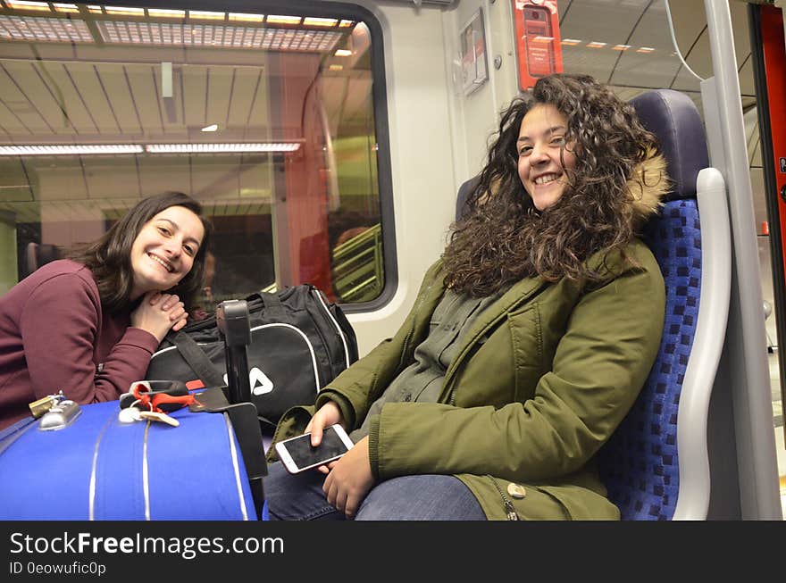 Happy smiling girls, maybe teenagers, on a train surrounded by luggage glad to be coming home or setting off for a holiday, background train interior. Happy smiling girls, maybe teenagers, on a train surrounded by luggage glad to be coming home or setting off for a holiday, background train interior.